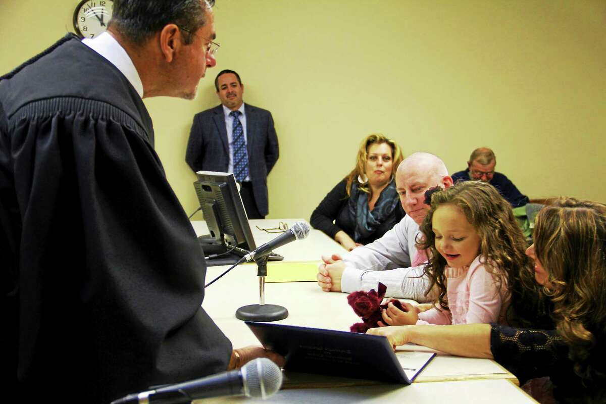 Judge James P. Ginocchio presents Nitara Stemmer with a teddy bear and her adoption certificate at the conclusion of her adoption proceeding Friday, Nov. 21, in Torrington.