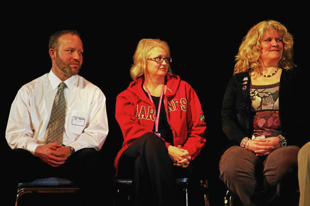 Teri Bradshaw (centers) a teacher at Torrington Middle School, sits next to fellow faculty member Lisa Owens-Hick and Jeremy Hinman, the son of a teacher at the school, during an assembly at the school recognizing veterans Friday. Bradshaw spoke about her experience serving with the U.S. Marines.