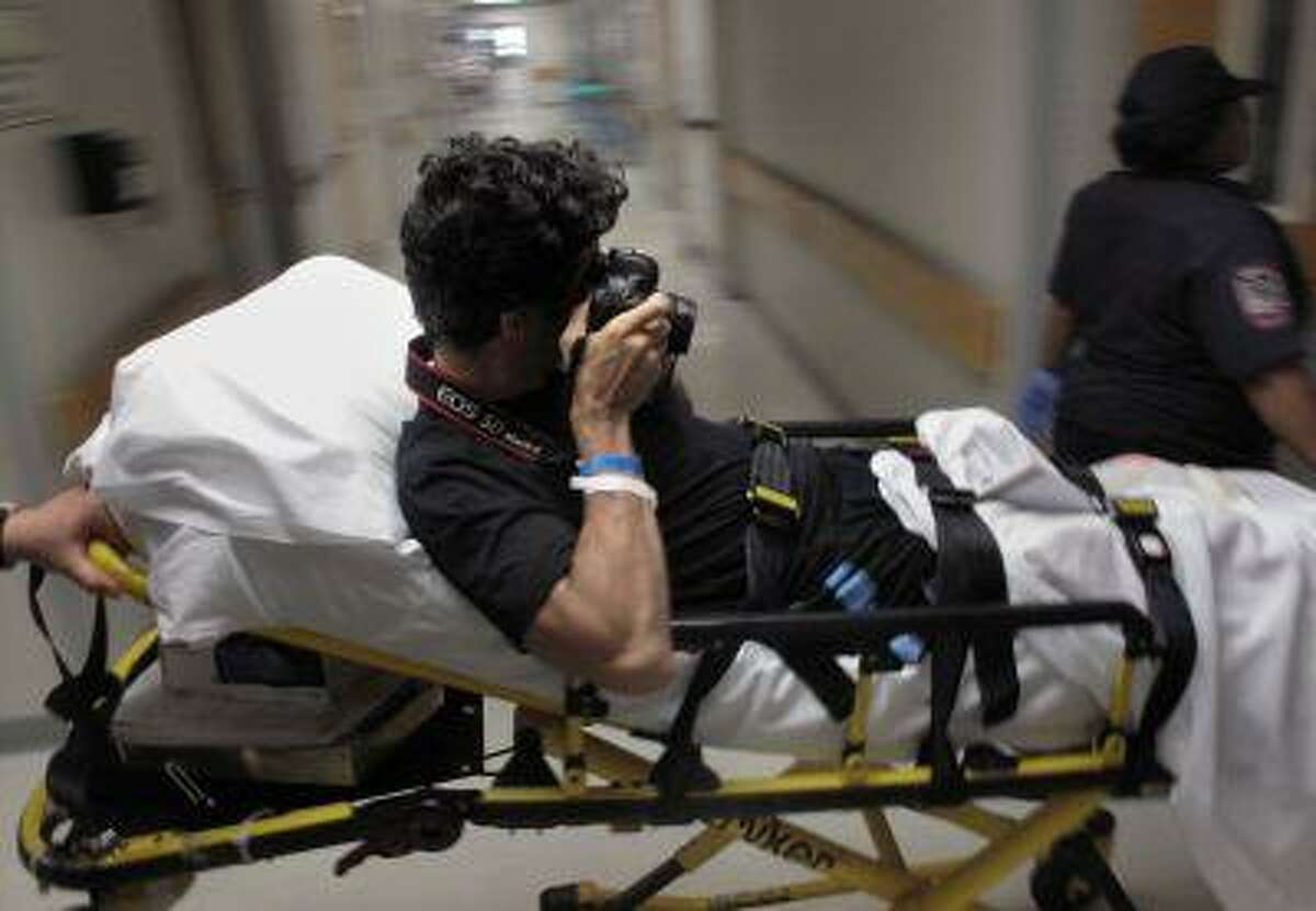 In this Aug. 25, 2009 picture, photographer Emilio Morenatti takes pictures as he is carried on a stretcher at University of Maryland Medical Center's R. Adams Cowley Shock Trauma Center in Baltimore, Md. For those who lost a limb or more in the Boston Marathon, Monday, April 15, 2013, was the day their world changed forever. Emilio's world changed also, on Tuesday, Aug. 11, 2009, when during his embed in southern Afghanistan with the U.S. military as a photographer for The Associated Press, which was to have been his last patrol before going home, the eight-wheel armored Stryker vehicle where he was traveling in with U.S soldiers hit a roadside bomb and flipped over, knocking him unconscious. Morenatti lost his leg in the bomb blast. (AP Photo/Enric Marti)