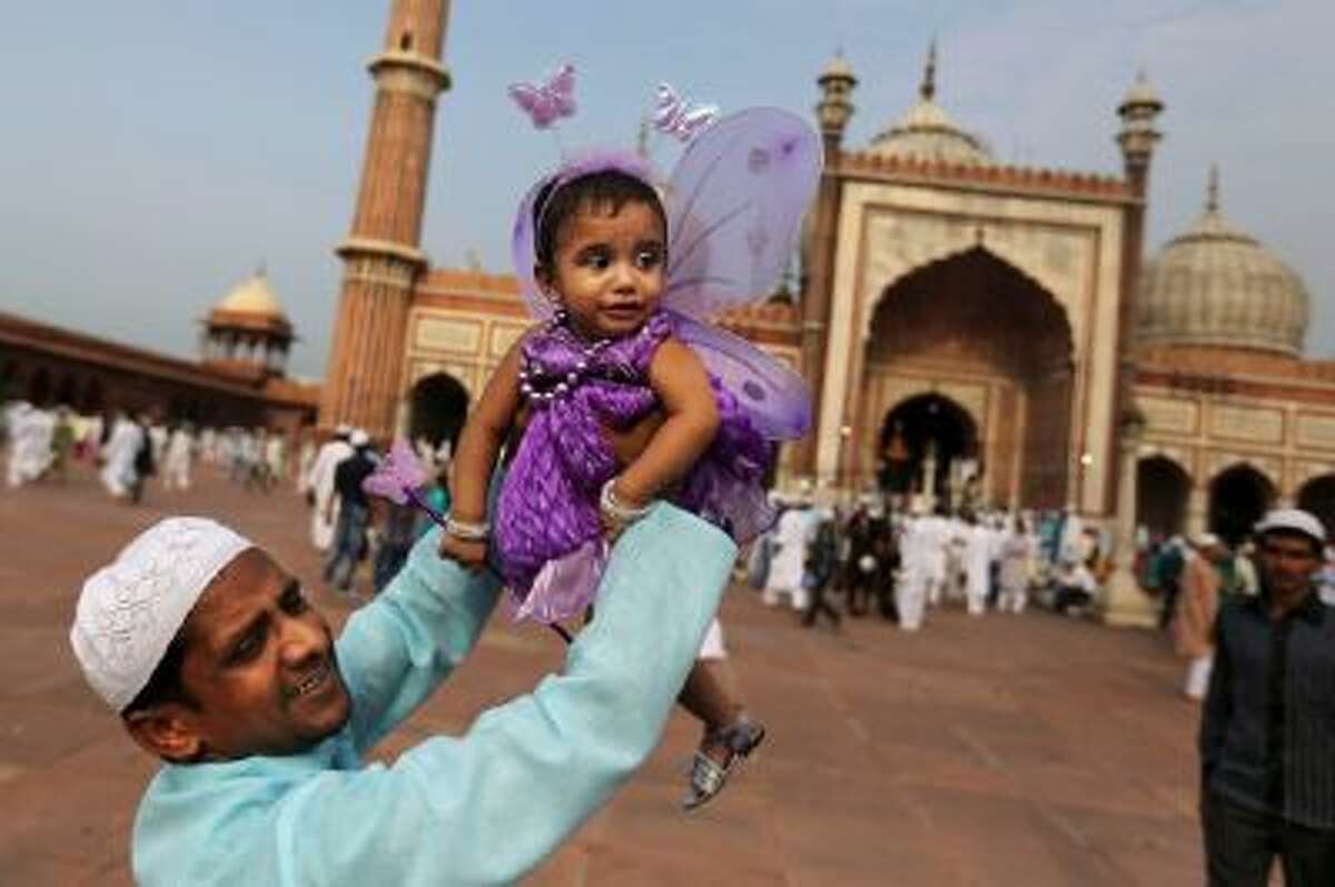 An Indian Muslim man holds up his daughter after Eid al-Fitr prayers at the Jama Masjid in New Delhi, India.