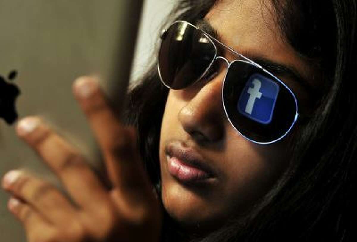 The 'Facebook' logo is reflected in a young Indian woman's sunglasses as she browses on a tablet in Bangalore on May 15, 2012.