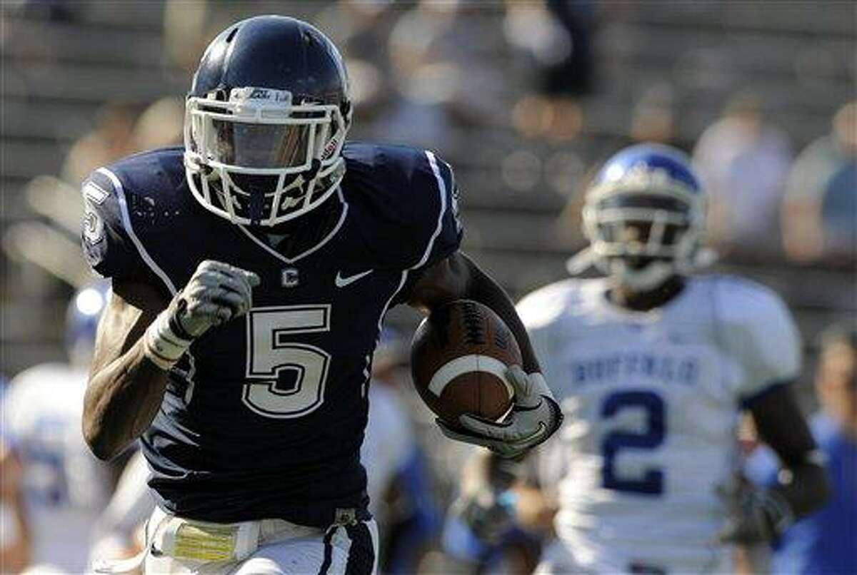 Connecticut's Blidi Wreh-Wilson returns an interception 46 yards for a touchdown as Buffalo's Marcus Rivers looks on during the second half of Connecticut's 45-21 victory in an NCAA football game in East Hartford, Conn., on Saturday, Sept. 25, 2010. (AP Photo/Fred Beckham)