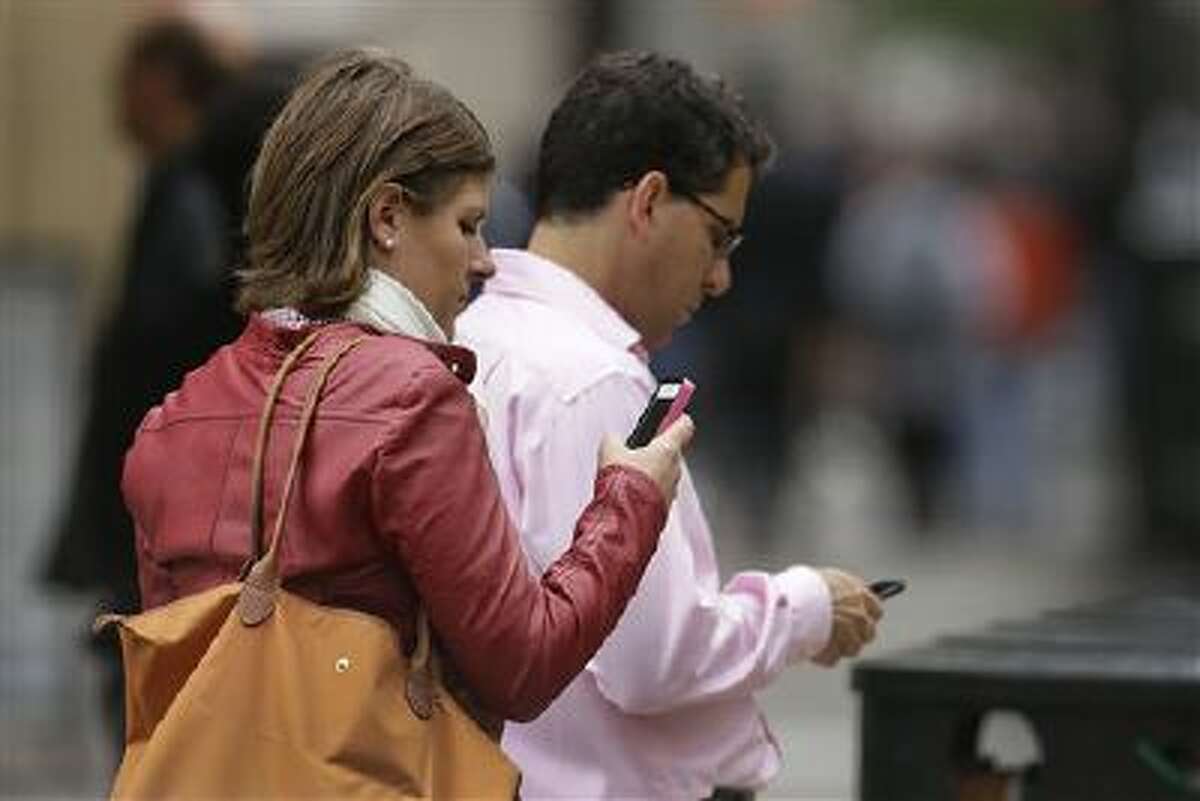 In this June 5, 2013, file photo, people use cellphones in downtown San Francisco.