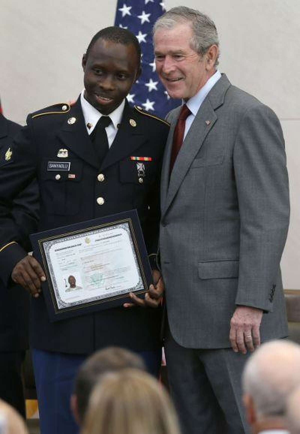 Former President George W. Bush, right, posses for a photo with Taofeek Adeyemi Sanyaolu, of Nigeria, with his U.S. citizen certificate after a ceremony at the The George W. Bush Presidential Center in Dallas, Wednesday, July 10, 2013. Twenty new citizens took the oath of U.S. citizenship at the former president's library. (AP Photo/LM Otero)