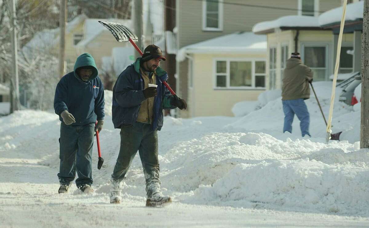 A couple of shovelers walk down North Street looking to remove snow Wednesday, Nov. 19, 2014, in Batavia, N.Y.