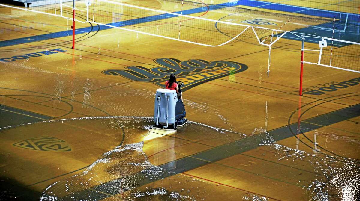 A worker begins the task of cleaning up at least an inch of water covering the playing floor at Pauley Pavilion, home of UCLA basketball, after a broken 30-inch water main under nearby Sunset Boulevard caused flooding that inundated several areas of the UCLA campus in the Westwood section of Los Angeles on Tuesday, July 29, 2014. (AP Photo/Mike Meadows)