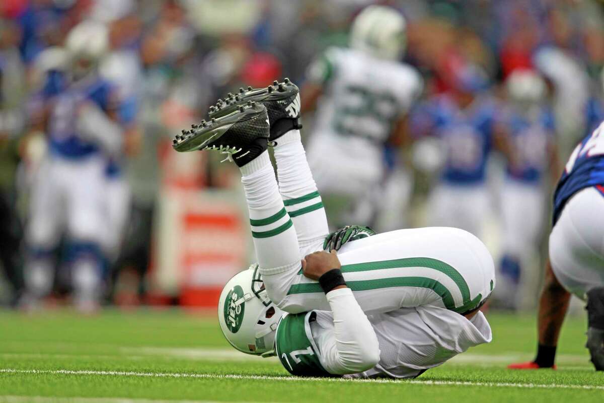 New York Jets quarterback Geno Smith gets knocked over by a Buffalo Bill during the first half of Sunday’s game in Orchard Park, N.Y.