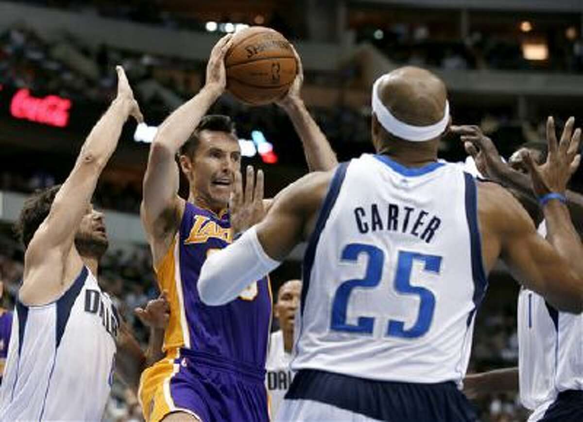 Los Angeles Lakers guard Steve Nash, center, goes up to pass from beneath the basket as Dallas Mavericks' Jose Calderon, left, of Spain, and Vince Carter (25) defend in the first half of an NBA basketball game, Tuesday, Nov. 5, 2013, in Dallas.