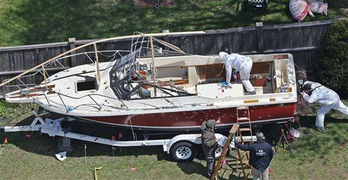 Investigators from the FBI inspect the boat where Boston Marathon bombing suspect Dzhokhar Tsarnaev was found hiding on Friday night in a backyard in Watertown, Mass., Tuesday, April 23, 2013. There is blood spattered on the wheel fender of the trailer and bullet holes in the hull of the boat. Tsarnaev had gunshot wounds to the head, neck, legs and hands when he was captured hiding out in the boat on Friday night, April 19, 2013. (AP Photo/The Boston Globe, David L. Ryan) BOSTON HERALD OUT; QUINCY OUT; NO SALES