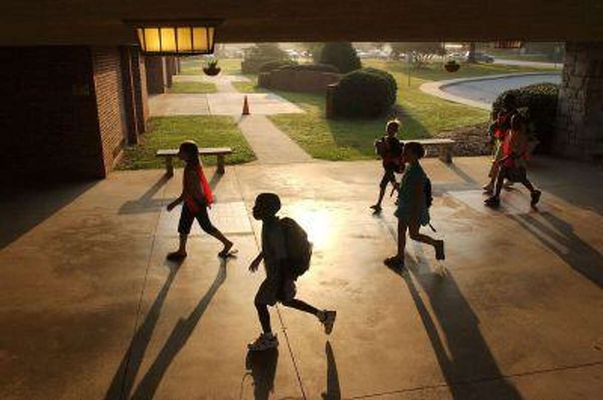 In this Aug. 25, 2006 photo, Whitehall Elementary School children, including safety patrol fifth graders wearing orange vests, walk back into school as the 8 a.m. bell and start of a school day nears, in Anderson, S.C. (AP Photo/Independent-Mail, Ken Ruinard, File)