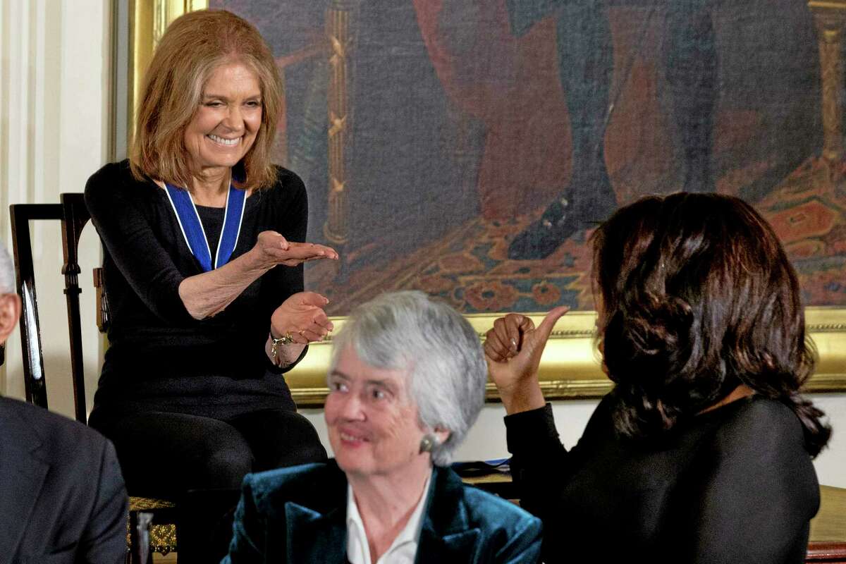 Women’s rights activist Gloria Steinem, left, gestures toward Oprah Winfrey, as Oprah gives a “thumbs up” after Steinem during a ceremony in the East Room of the White House in Washington, Wednesday, Nov. 20, 2013, where President Barack Obama awarded Presidential Medal of Freedoms. At center is fellow recipient judge Patricia Wald.