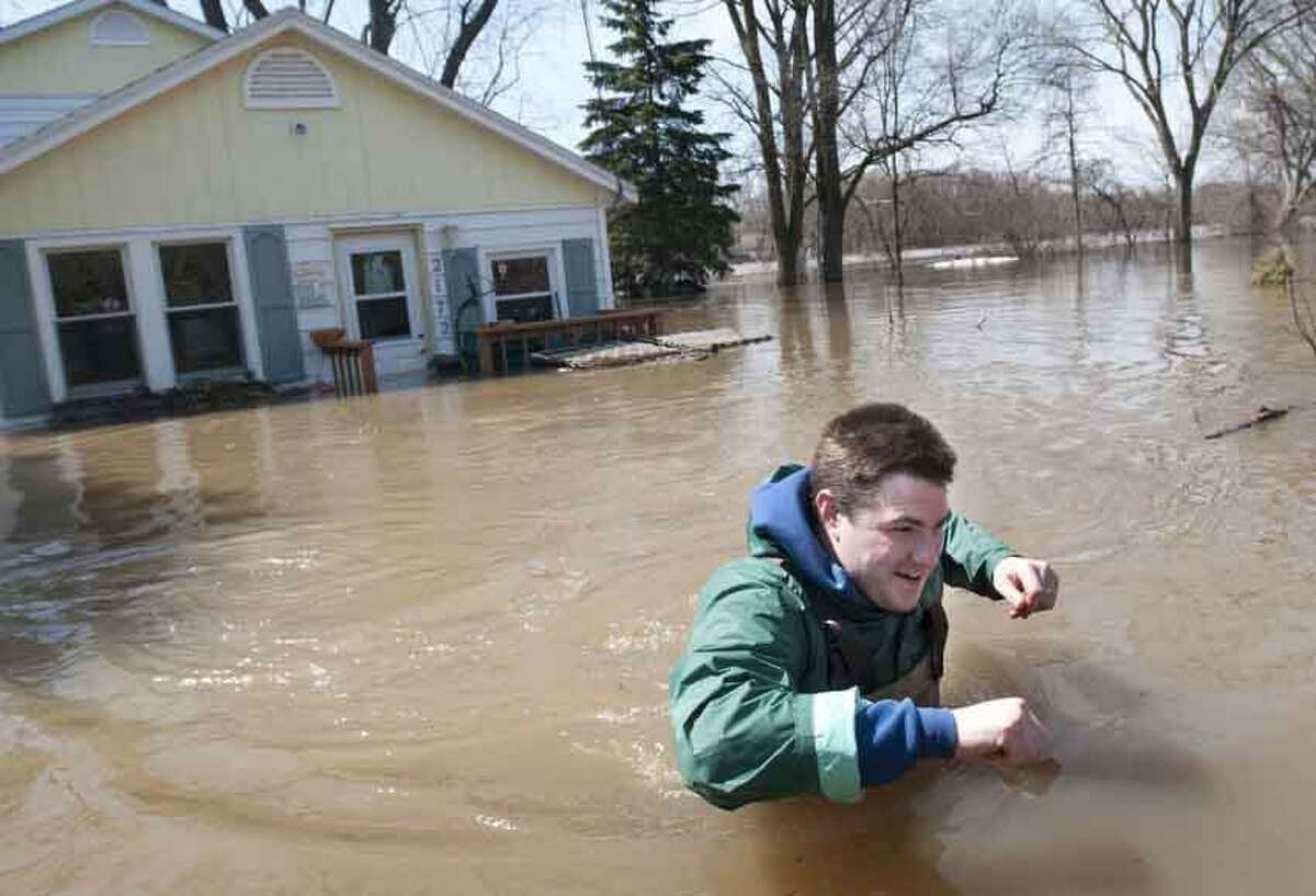 Joe Biggerstaff wades away from his mother's Konkle Drive home on the Grand River north of downtown Grand Rapids, Mich., Sunday, April 21, 2013. The rising Grand River has driven hundreds of people from their homes in several western Michigan communities and was pushing Sunday toward a record high near Grand Rapids. (AP Photo/MLive.com, Chris Clark)