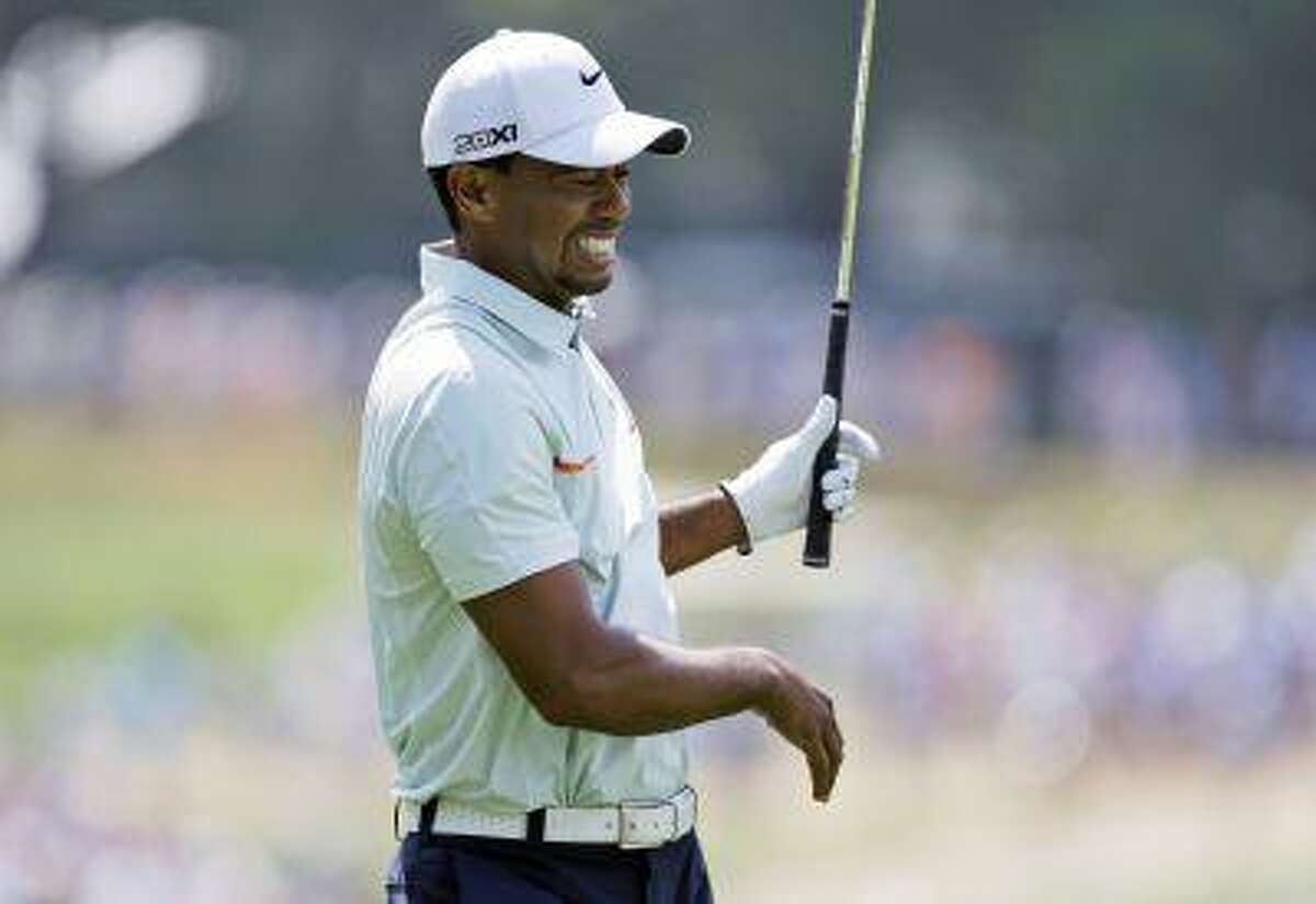 In this June 15, 2013, file photo, Tiger Woods reacts after hitting from the rough on the fourth hole during the third round of the U.S. Open golf tournament at Merion Golf Club in Ardmore, Pa.