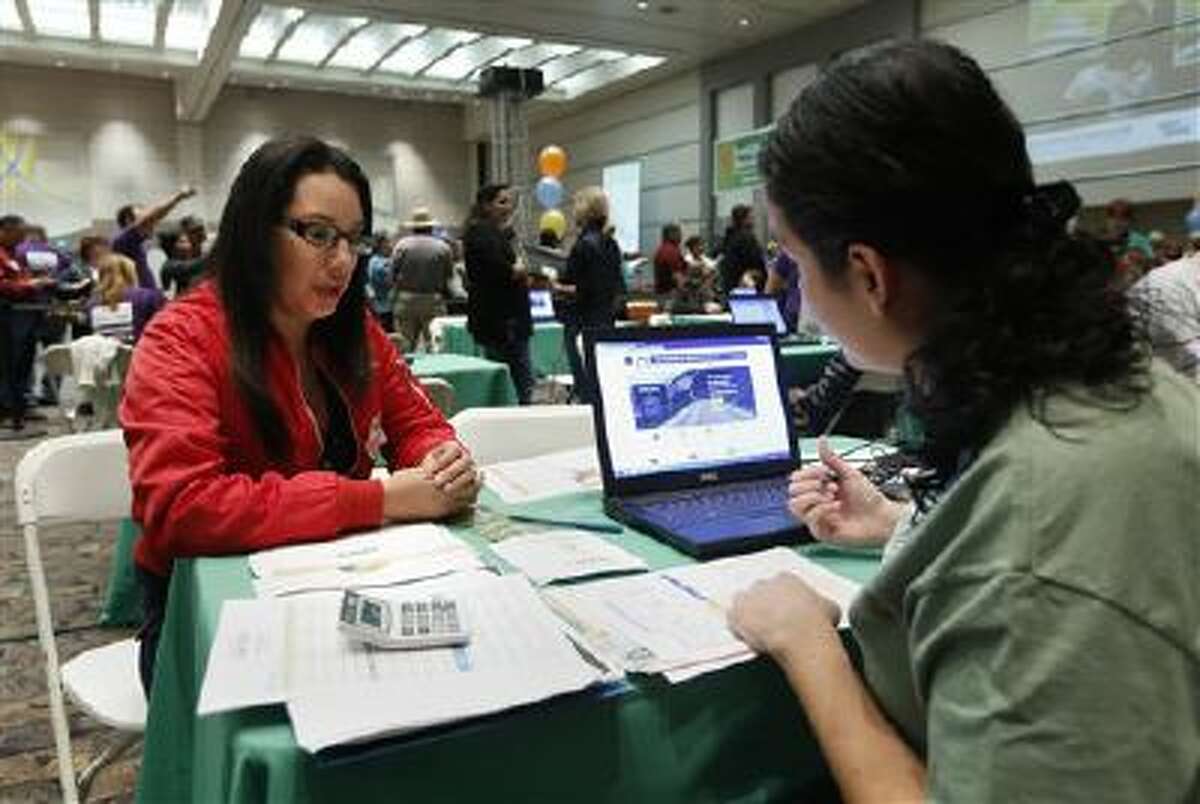 Cinthia Orozco gets help signing up for health insurance from Griselda Zamora, a health care specialist, in Sacramento, Calif.