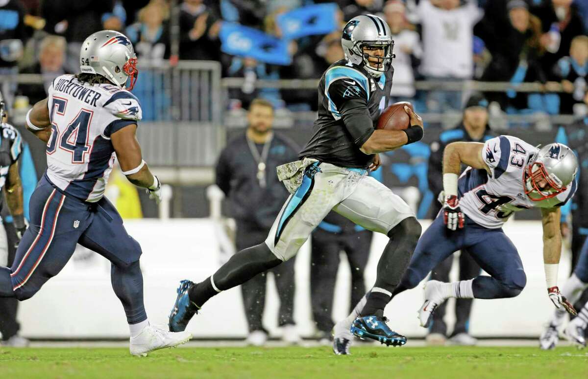 The Panthers’ Cam Newton, center, scrambles as the Patriots’ Dont’a Hightower, left, and Nate Ebner pursue during the second half of Monday’s game in Charlotte, N.C.