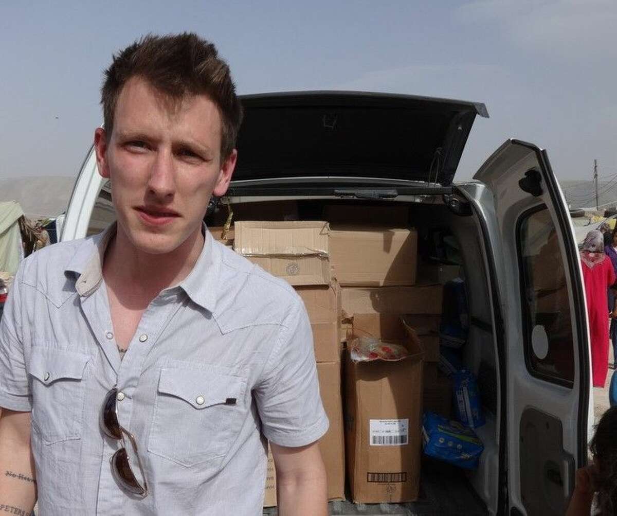 This undated file photo provided by the Kassig Family shows Peter Kassig standing in front of a truck filled with supplies for Syrian refugees. A new graphic video purportedly produced by Islamic State militants in Syria released Sunday Nov. 16, 2014 claims U.S. aid worker Kassig was beheaded.
