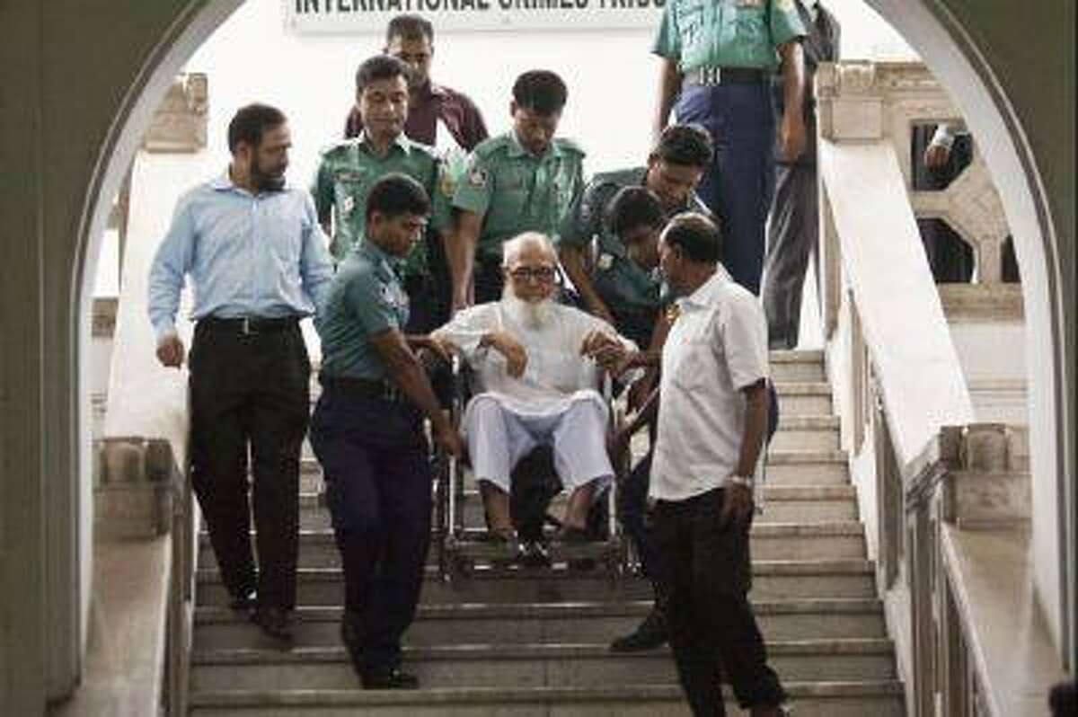 Ghulam Azam, center, former head of the opposition Jamaat-e-Islami party, is assisted by security personnel as he emerges from the Bangladesh International Crimes Tribunal in Dhaka on May 13, 2012.