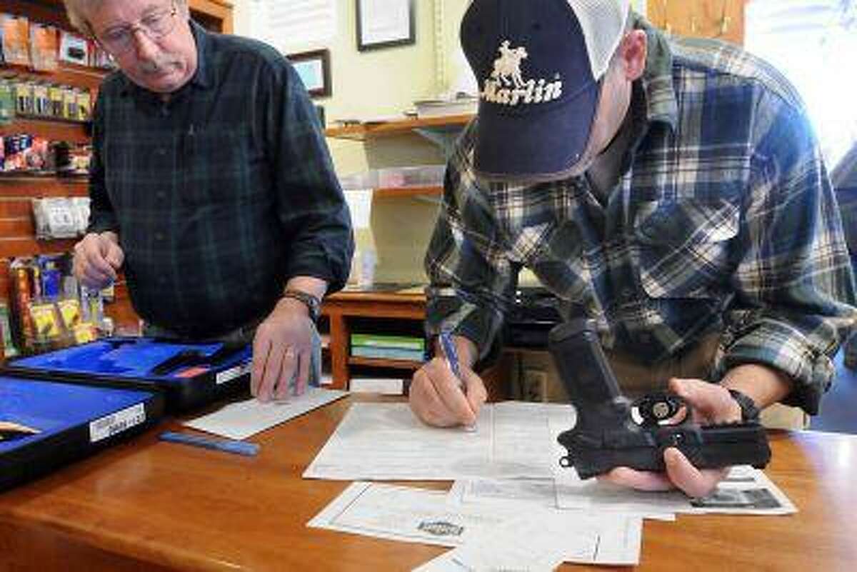At the TGS Outdoors shop in Branford. Co-owners Brian Owens left and Mike Higgins do the paperwork on the sale of a FNX-45 semi-automatic pistol. Gov. Dan Malloy signed a sweeping gun-control bill into law. (Mara Lavitt/New Haven Register)