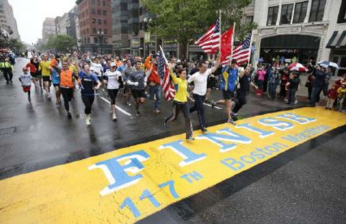 Runners who were unable to finish the Boston Marathon on April 15 because of the bombings cross the finish line on Boylston Street after the city allowed them to finish the last mile of the race in Boston on May 25.