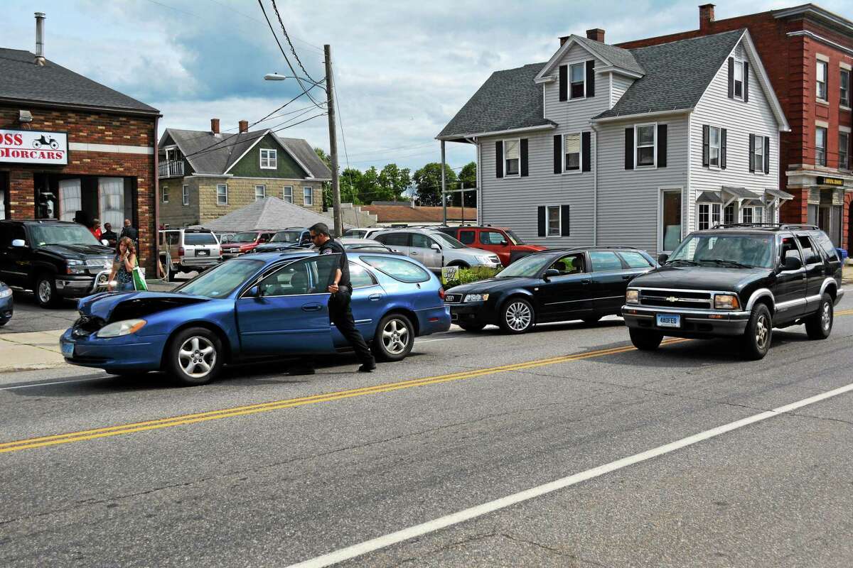 Jenny Golfin - Register Citizen. Torrington Police Officer Robert Simon moves one of the vehicles involved in a three-car accident on East Main Street out of the roadway to help clear the way for traffic Tuesday afternoon. The two station wagons, pictured at left, were involved in the accident.