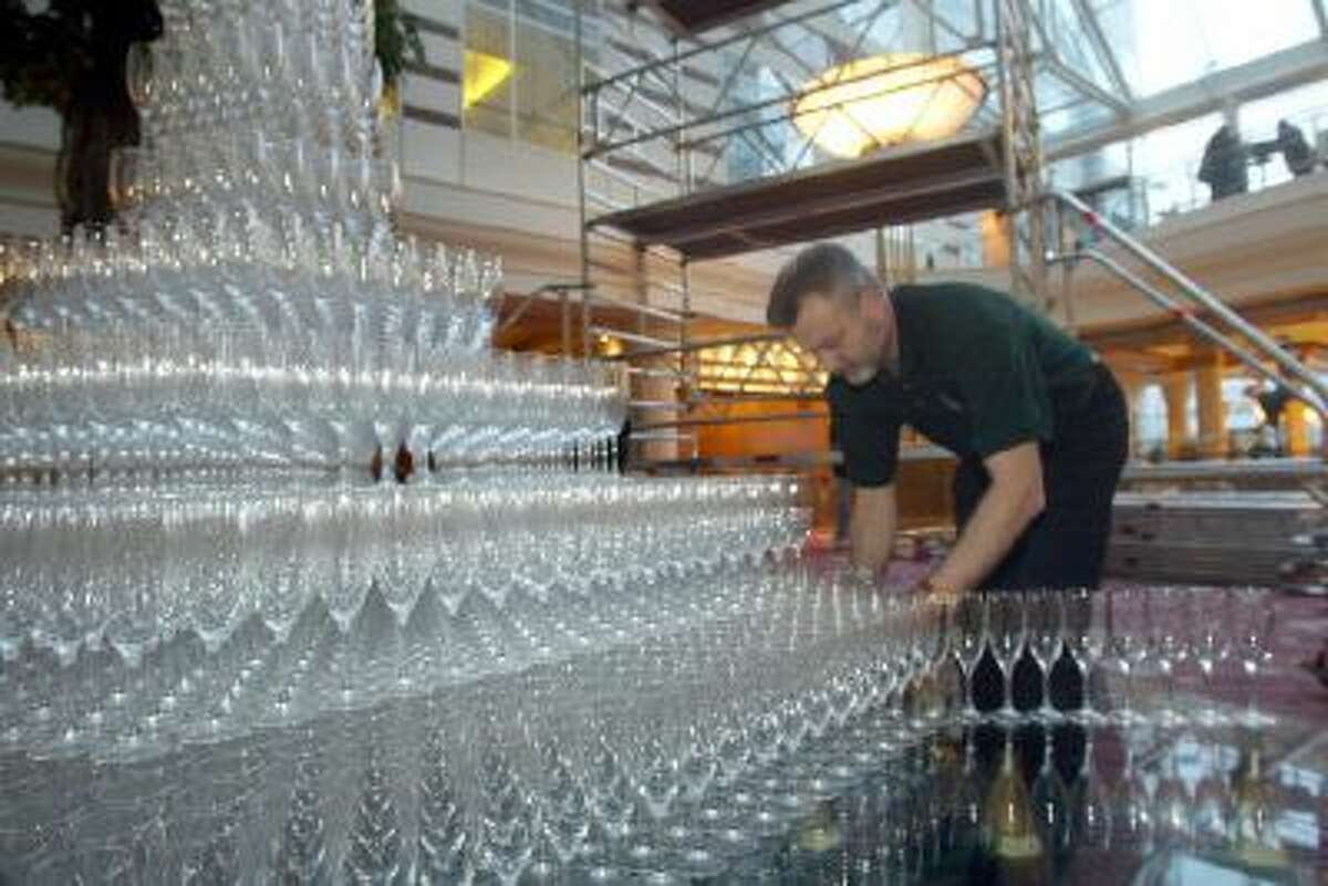 An employee of French champagne manufacturer Leclerc Briant stacks champagne flutes 08 February 2004 in Roissy in an attempt to break the Guiness World Record for the highest champagne fountain.