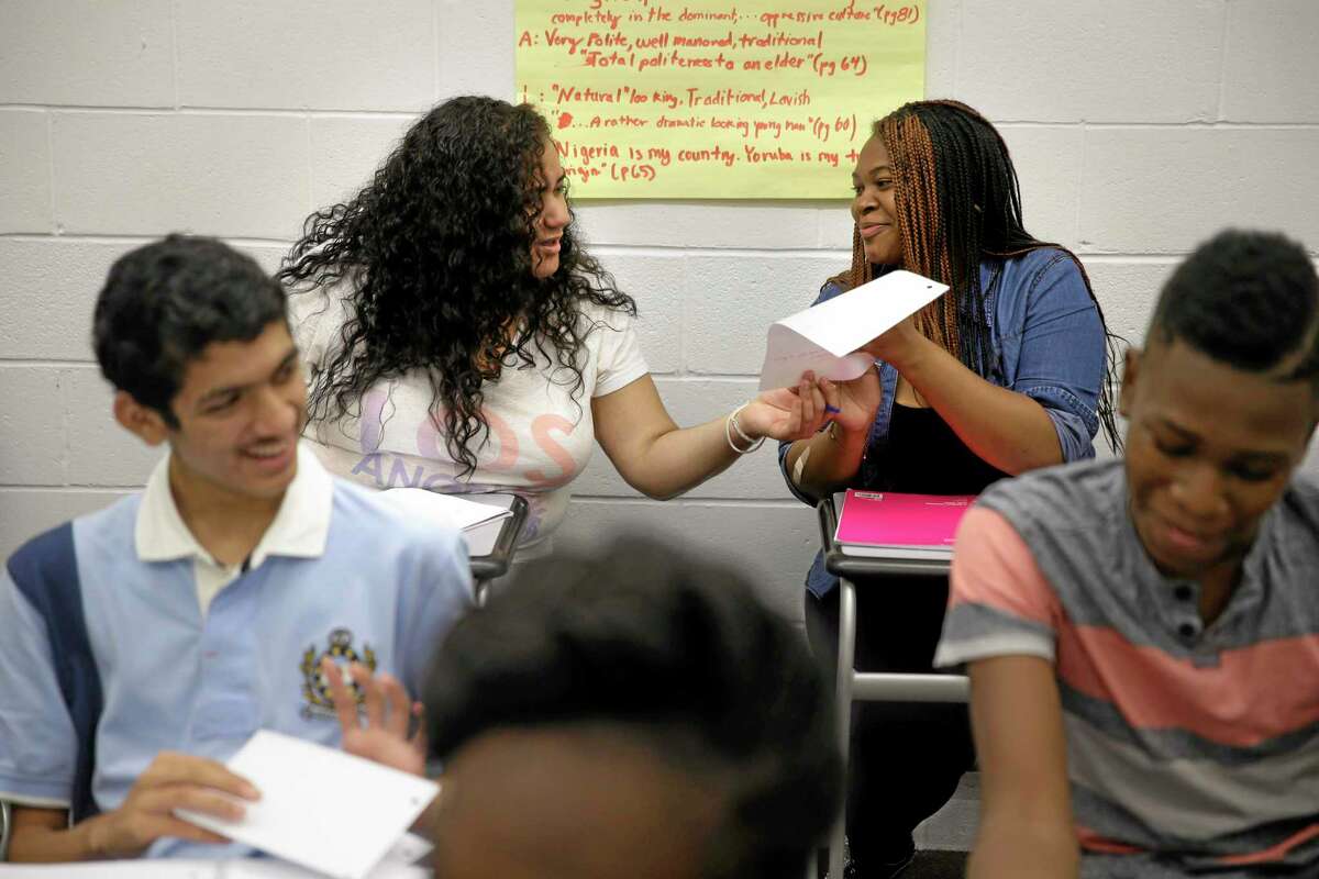 In this July 16, 2014 photo, Crystal Martinez, 18, second from left, and Reina Baltazar, 17, second from right, look at each others papers during their English class at an Upward Bound program in New York. This summer marks the 50th anniversary of Upward Bound, which was founded as an experimental program in 1964 as part of Lyndon B. Johnson's War on Poverty with a goal of helping students from low-income families get a college education. (AP Photo/Seth Wenig)
