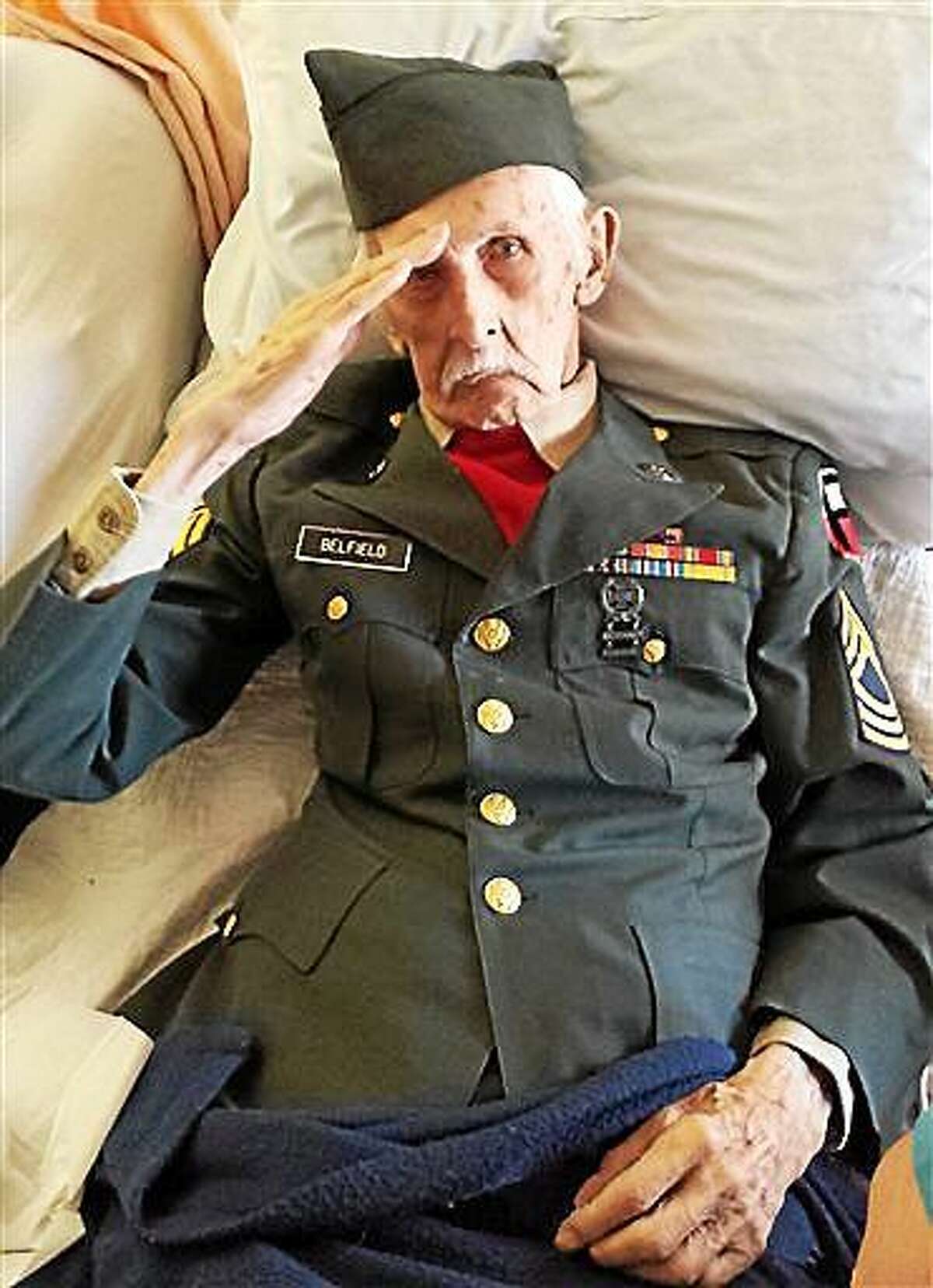 This Nov. 11, 2014 photo provided courtesy of Nancy McKiernan of Baptist Health Nursing and Rehabilitation Center in Glenville, N.Y., shows 98-year-old World War II veteran Justus Belfield saluting on Veterans Day. The Daily Gazette of Schenectady reports Belfield had worn his Army uniform every Veterans Day since he and his wife moved into the nursing home outside Albany several years ago. On Tuesday, the former master sergeant wasn't able to get out of bed to participate in the facility's Veterans Day festivities, so he had the staff dress him in his uniform. Belfield passed away the next day. (AP Photo/Courtesy of Nancy McKiernan/Baptist Health Nursing and Rehabilitation Center)