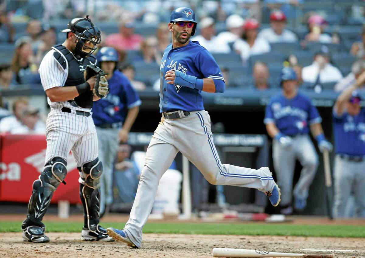 Yankees catcher Francisco Cervelli, left, looks down as Toronto’s Jose Bautista scores on Dioner Navarro’s go-ahead, ninth-inning RBI single Sunday.