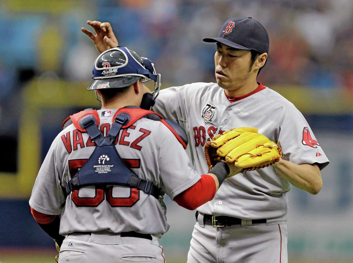 Red Sox closer Koji Uehara, left, hugs catcher Christian Vazquez after Boston’s win over the Rays on Sunday.