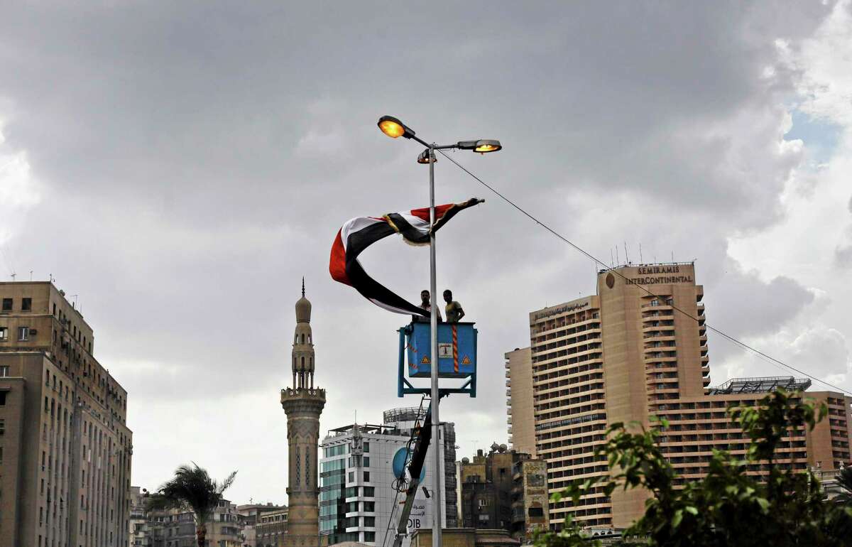 Egyptian laborers hang a national flag on a street light two days before the commemoration of deadly clashes with security forces in 2011, in Tahrir Square, Cairo, Egypt, Sunday, Nov. 17, 2013. Egyptian authorities are building a memorial in Cairo’s Tahrir Square dedicated to protesters killed in the country’s turmoil, only days before a highly charged second anniversary marks one of the fiercest confrontations between demonstrators and security forces in the area that left scores dead. (AP Photo/Nariman El-Mofty)