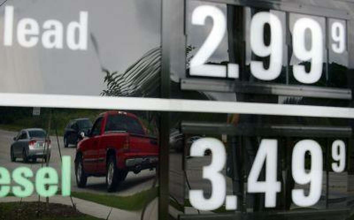 In this Monday, July 1, 2013 photo, vehicles are reflected in a sign advertising unleaded gas for $2.99 at a QuikTrip station in Greenville, S.C. Gasoline prices are on a summer slide, giving U.S. drivers a break as they set out for the beach and other vacation spots for the Fourth of July. (AP Photo/Rainier Ehrhardt)