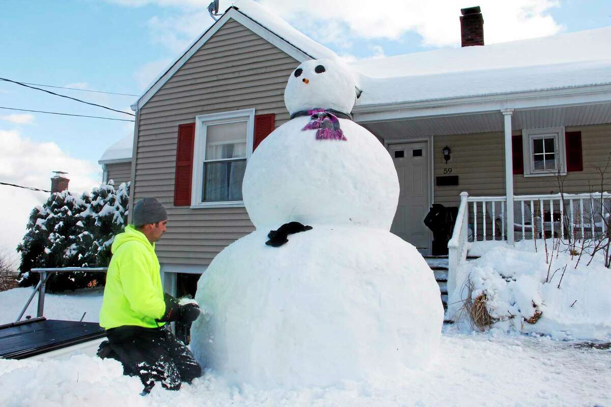 Brandon Blatchley builds an 8-foot-tall snowman on his lawn on Eggleston St in Torrington on Friday.