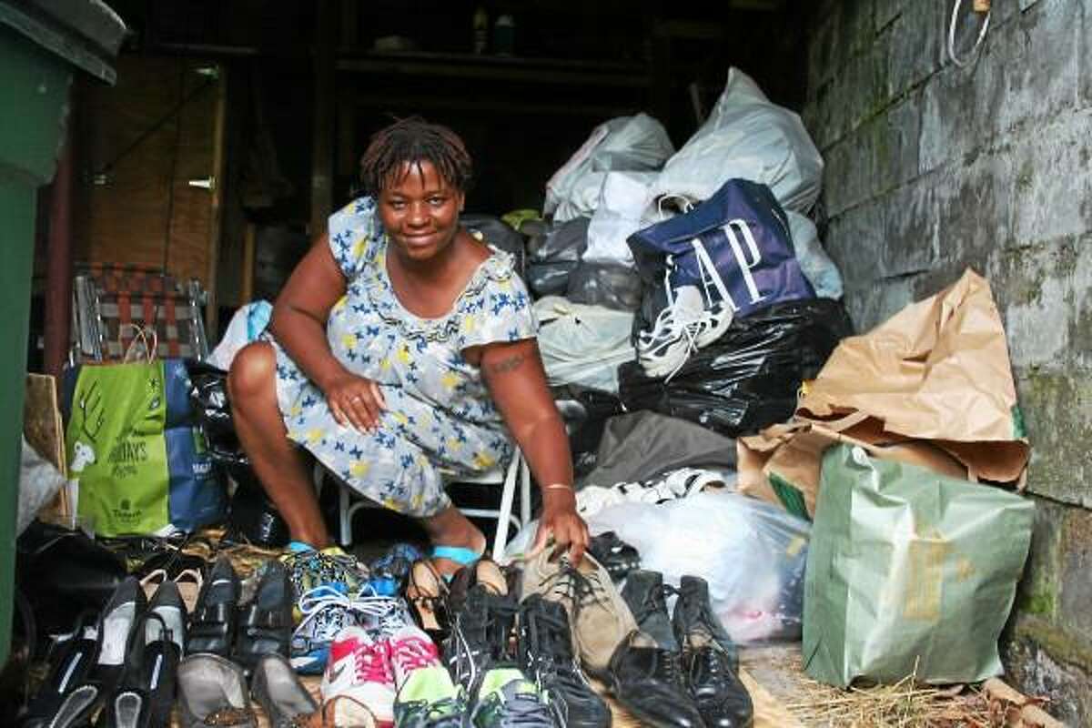 Michelle Pickering crouches as she organizes donated shoes in her home in Torrington. She is hoping to collect 30,000 shoes to donate to people in Tanzania. Camela Kiernan - Submitted photo