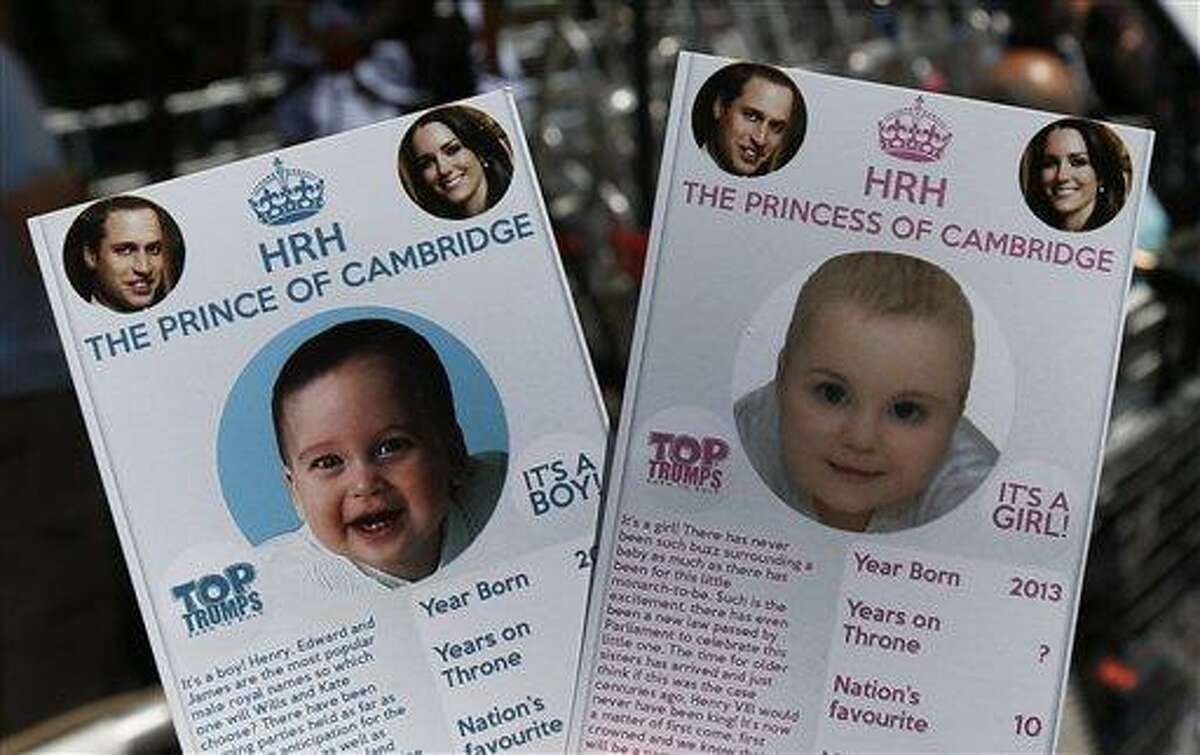 Cards depicting the 'royal baby' either as a boy or a girl, specially made by a games company as a publicity stunt, are pictured here, backdropped by members of the media waiting across from the St. Mary's Hospital exclusive Lindo Wing in London, Thursday, July 11, 2013. Media are preparing for royal-mania as Britain's Duchess of Cambridge plans to give birth to the new third-in-line to the throne in mid-July, at the Lindo Wing. Cameras from all over the world are set to be jostling outside for an exclusive first glimpse of Britain's Prince William and the Duchess of Cambridge's first child. (AP Photo/Lefteris Pitarakis)