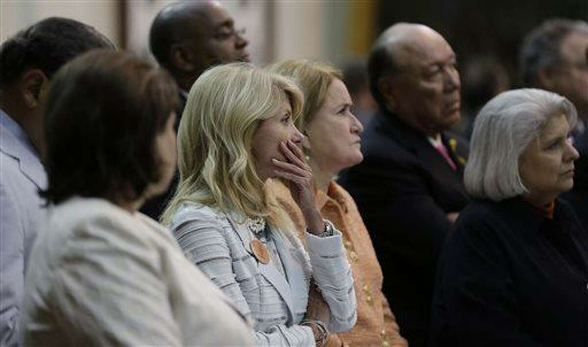 Sen. Wendy Davis, D-Fort Worth, center, holds her hand to her mouth as she stands with fellow senators after she was called for a third and final violation in rules to end her filibuster attempt to kill an abortion bill, Tuesday, June 25, 2013, in Austin, Texas. The bill would ban abortion after 20 weeks of pregnancy and force many clinics that perform the procedure to upgrade their facilities and be classified as ambulatory surgical centers. (AP Photo/Eric Gay)