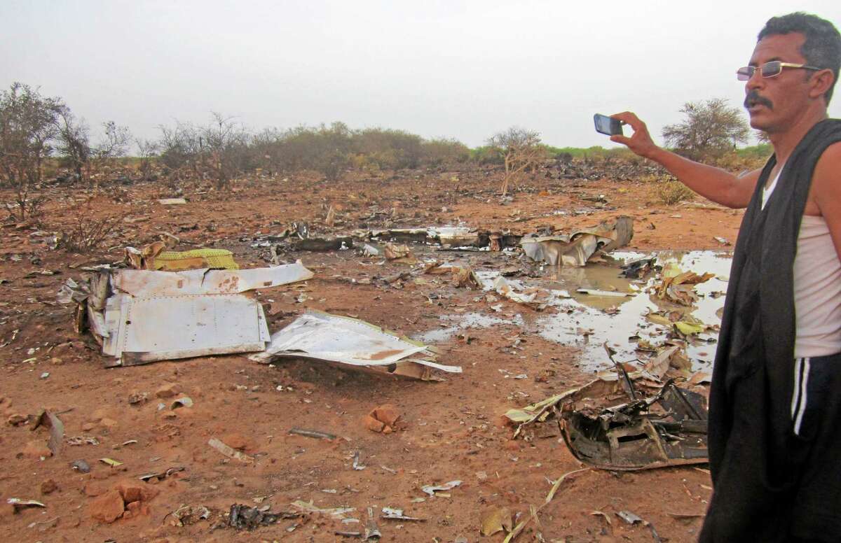 This photo provided on Friday, July 25, 2014, by the Burkina Faso Military shows a man at the site of the plane crash in Mali. French soldiers secured a black box from the Air Algerie wreckage site in a desolate region of restive northern Mali on Friday, the French president said. Terrorism hasn't been ruled out as a cause, although officials say the most likely reason for the catastrophe that killed all onboard is bad weather. At least 116 people were killed in Thursday's disaster, nearly half of whom were French. (AP Photo/Burkina Faso Military)