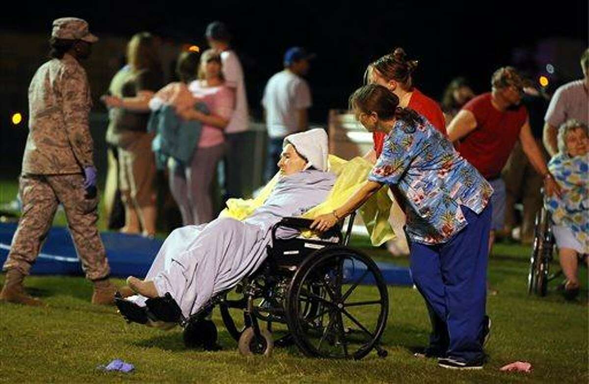 Emergency workers assist an elderly person at a staging area at a local school stadium Wednesday, April 17, 2013, in West, Texas. An explosion Wednesday night at a fertilizer plant near Waco sent flames shooting high into the night sky, leaving the factory a smoldering ruin, causing major damage at nearby buildings and injuring numerous people. (AP Photo/Waco Tribune Herald, Rod Aydelotte)