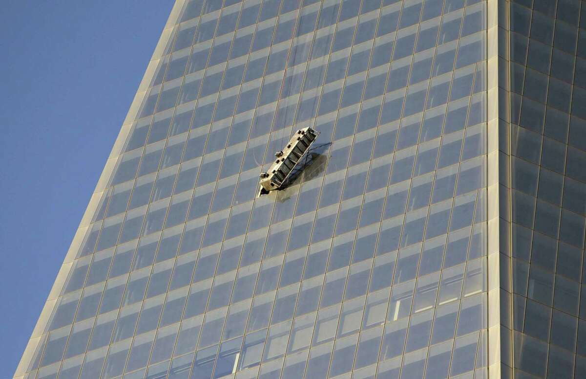 A scaffolding dangles precariously on the side of 1 World Trade Center hours after two window washers were rescued by firefighters who cut through a window to reach them, Wednesday, Nov. 12, 2014, in New York.