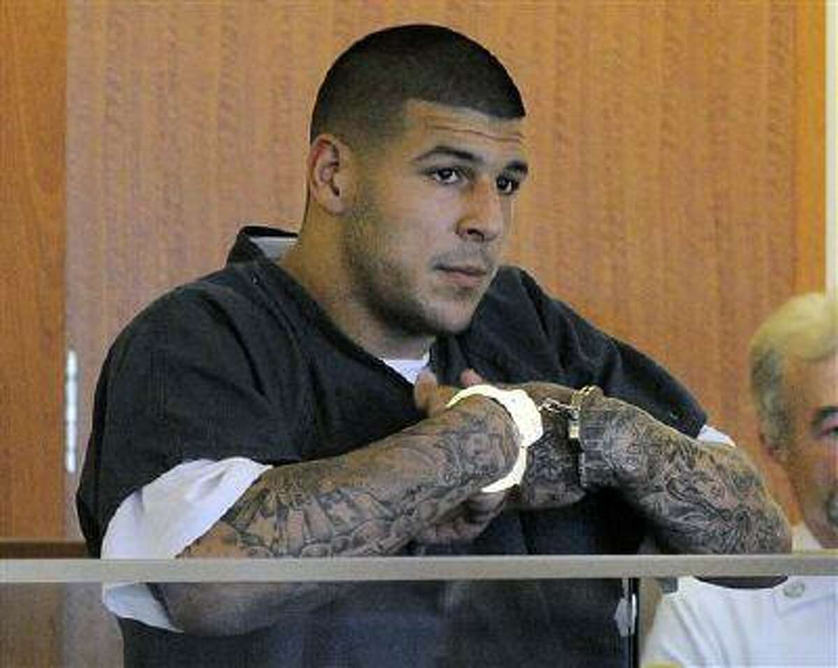 FILE - Former New England Patriots football tight end Aaron Hernandez stands during a bail hearing in Fall River Superior Court in this June 27, 2013 file photo taken in Fall River, Mass. An associate of former New England Patriots tight end Aaron Hernandez said he was told Hernandez fired the shots that resulted in the death of a semi-pro football player, according to documents filed in Florida. The records say Hernandez associate Carlos Ortiz told Massachusetts investigators that another man, Ernest Wallace, said Hernandez shot Lloyd in an industrial park near Hernandez's home in North Attleborough. (AP Photo/Boston Herald, Ted Fitzgerald, Pool)