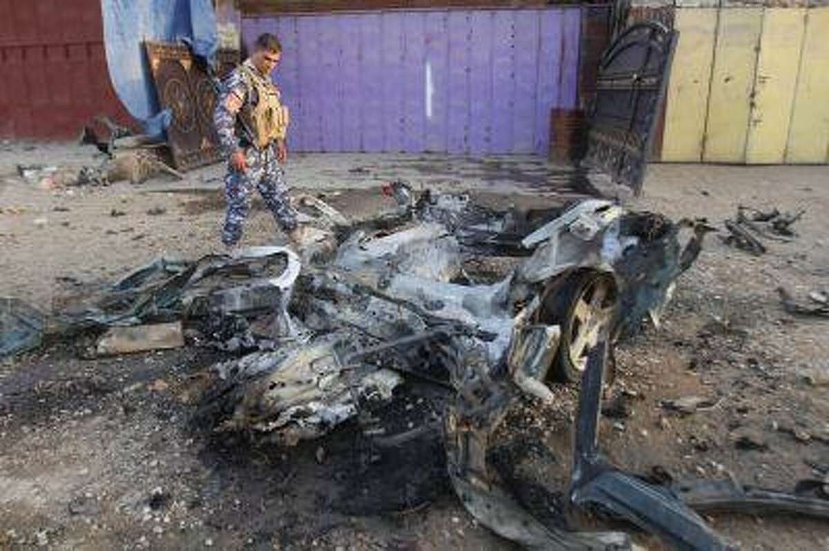 An Iraqi policeman inspects the site of a car bomb attack in Kirkuk, 250 km (155 miles) north of Baghdad, July 11, 2013. Two civilians were wounded in the car bomb attack, police said. REUTERS/Ako Rasheed (IRAQ - Tags: CIVIL UNREST POLITICS)