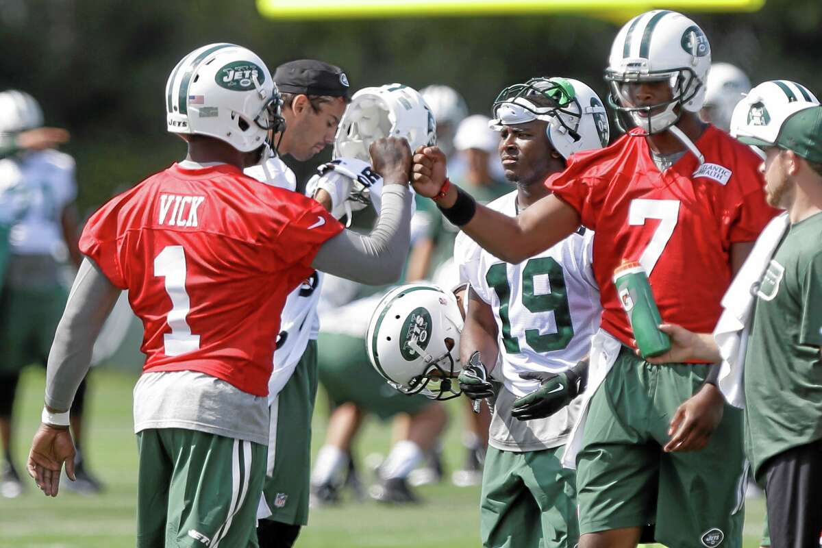 New York Jets quarterbacks Michael Vick (1) and Geno Smith (7) fist bump at training camp Thursday in Cortland, N.Y.