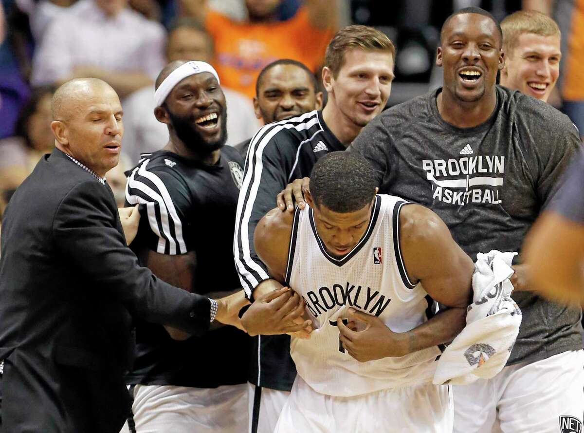 The Brooklyn Nets’ Joe Johnson is surrounded by teammates after making the game-winning shot in overtime against the Suns on Friday night in Phoenix.
