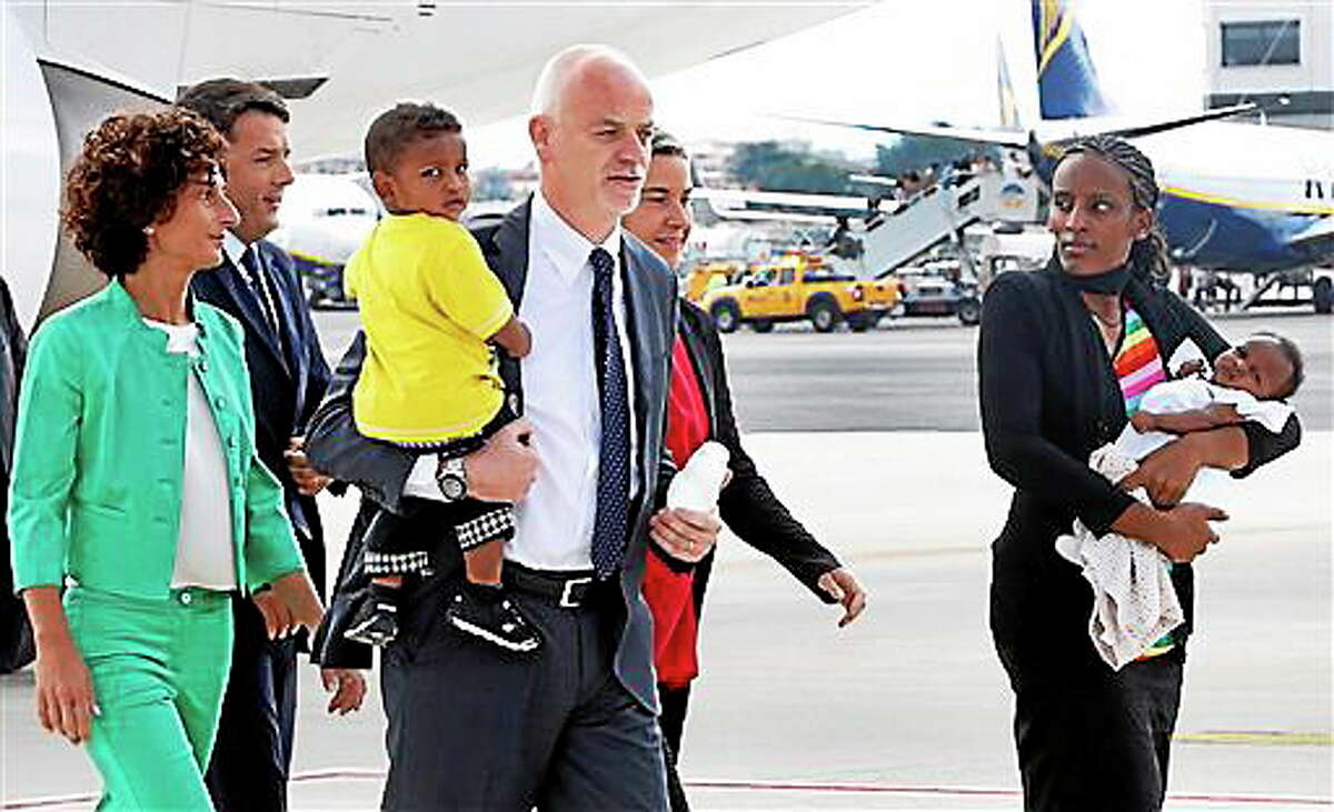 Meriam Ibrahim, from Sudan, right, holds her baby girl Maya, accompanied by Italian deputy Foreign Miinister Lapo Pistelli, holding her son Martin, followed by Italian Foreign Minister Federica Mogherini, second from right, Italian Premier Matteo Renzi, second from left, and his wife Agnese Landini, after landing from Khartoum, at Ciampino's military airport, on the outskirts of Rome, Thursday, July 24, 2014. The Sudanese woman who was sentenced to death in Sudan for refusing to recant her Christian faith has arrived in Italy along with her family, including an infant born in prison. An Italian diplomat who accompanied the family from Sudan said Italy leveraged its historic ties within the Horn of Africa region to help win her release. (AP Photo/Riccardo De Luca)