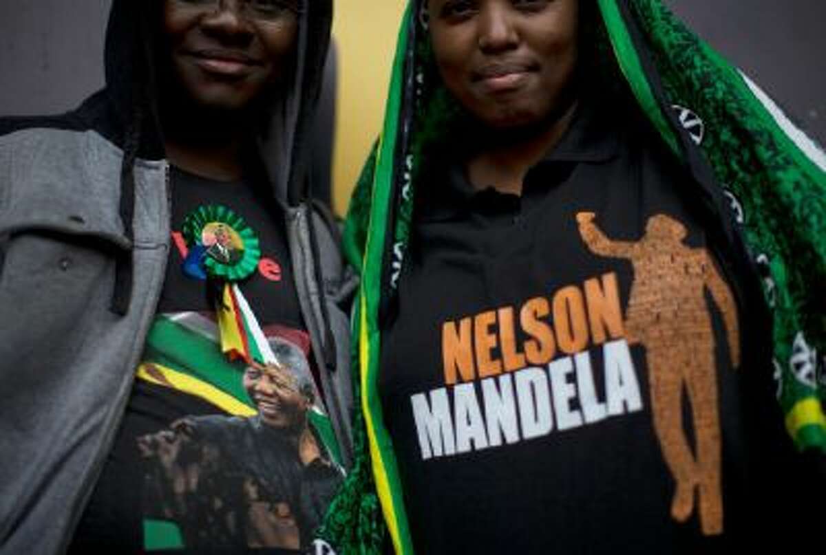 Mourners display their Nelson Mandela t-shirts as they wait for the memorial service for former South African president Nelson Mandela at the FNB Stadium in Soweto near Johannesburg, Tuesday, Dec. 10, 2013.