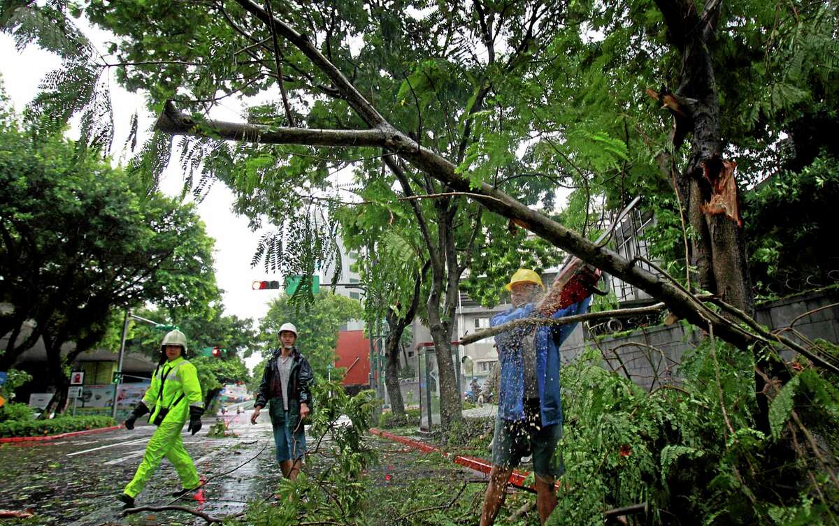 A city maintenance crew member removes fallen trees from a main road as Typhoon Matmo passes Taipei, Taiwan, Wednesday, July 23, 2014. The eye of Typhoon Matmo made landfall in eastern Taiwan early Wednesday bringing with it heavy rains and winds with gusts over 140 kilometers (85 miles) per hour.