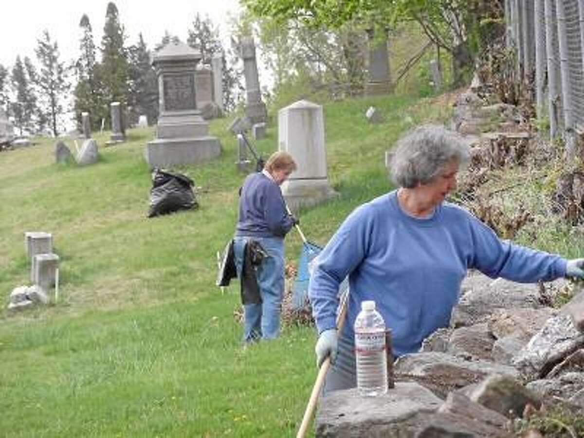 Torrington residents clean the grounds of a cemetery during a 2012 Earth Day cleanup. -- Register Citizen File Photo