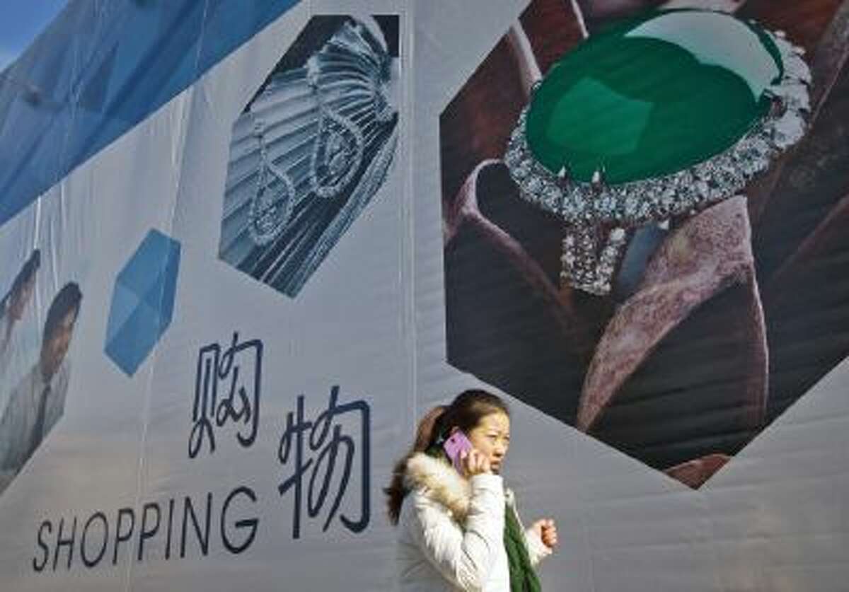 A woman talks on her mobile phone as she walks past an advertisement billboard for a new shopping mall in Beijing.