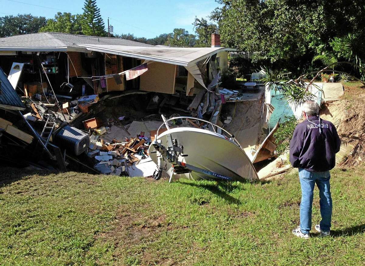 A man observes a sinkhole has swallowed parts of two houses in Dunedin, Fla. on Thursday, Nov. 14, 2013. Dunedin Deputy Fire Chief Trip Barrs said the hole appeared to be about 12-feet wide when officials arrived on the scene. Residents of the neighboring houses also were evacuated as a precaution. There are no reports of injuries. (AP Photo/The Tampa Tribune, Luke Johnson) ST. PETERSBURG OUT; LAKELAND OUT; BRADENTON OUT; MAGS OUT; LOCAL TV OUT; WTSP CH 10 OUT; WFTS CH 28 OUT; WTVT CH 13 OUT; BAYNEWS 9 OUT; THE TAMPA BAY TIMES OUT; LAKELAND LEDGER OUT; BRADENTON HERALD OUT; SARASOTA HERALD-TRIBUNE OUT; WINTER HAVEN NEWS CHIEF OUT