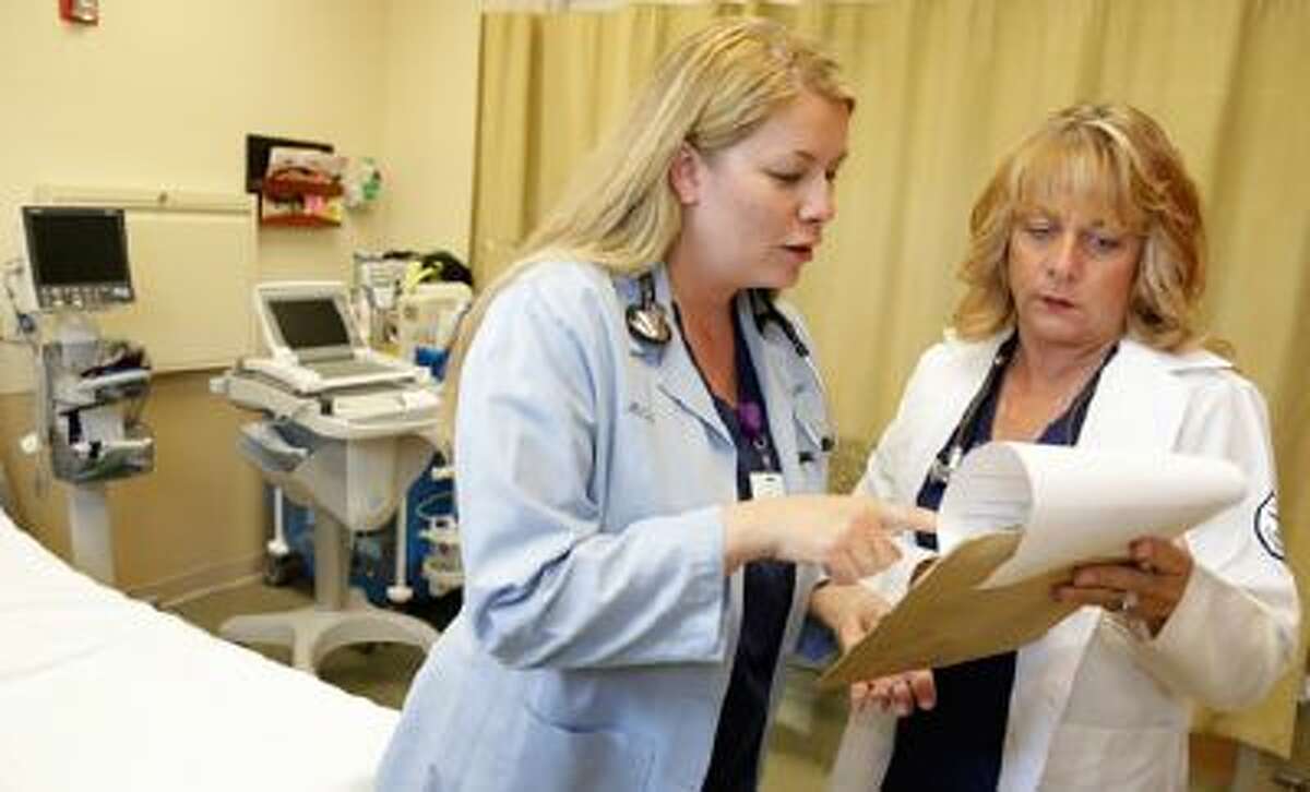 Nurse practitioners Michele Knappe, left, and Julie Zimmer go over a patient's chart at Ingalls Family Care Center in Flossmoor, Ill. The need for health care workers is expected to surge in the next decade, and several governors are pushing proposals designed to attract more qualified applicants.
