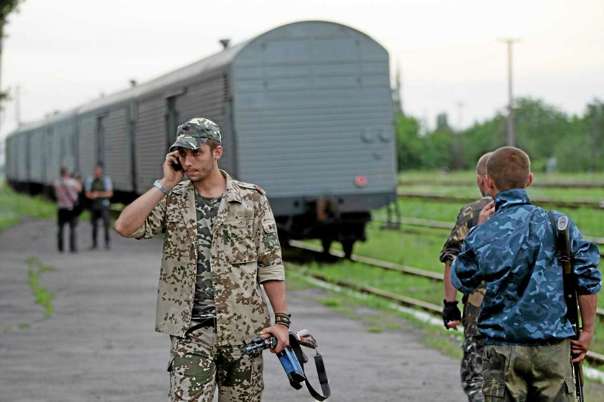 A pro-Russian rebel speaks on the phone as a refrigerated train loaded with bodies of the passengers departs the station in Torez, eastern Ukraine, 15 kilometers (9 miles) from the crash site of Malaysia Airlines Flight 17, Monday, July 21, 2014. (AP Photo/Vadim Ghirda)